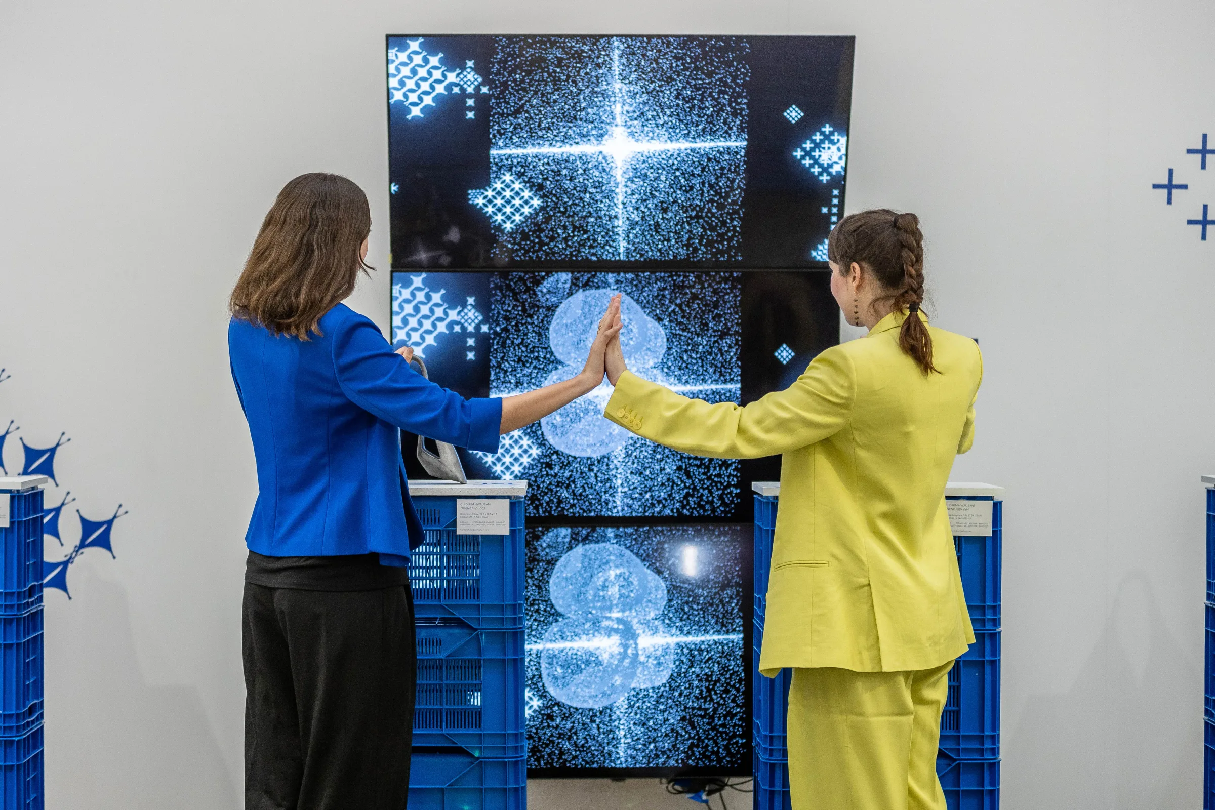 Two visitors completing the circuit, palms together before the generative screen