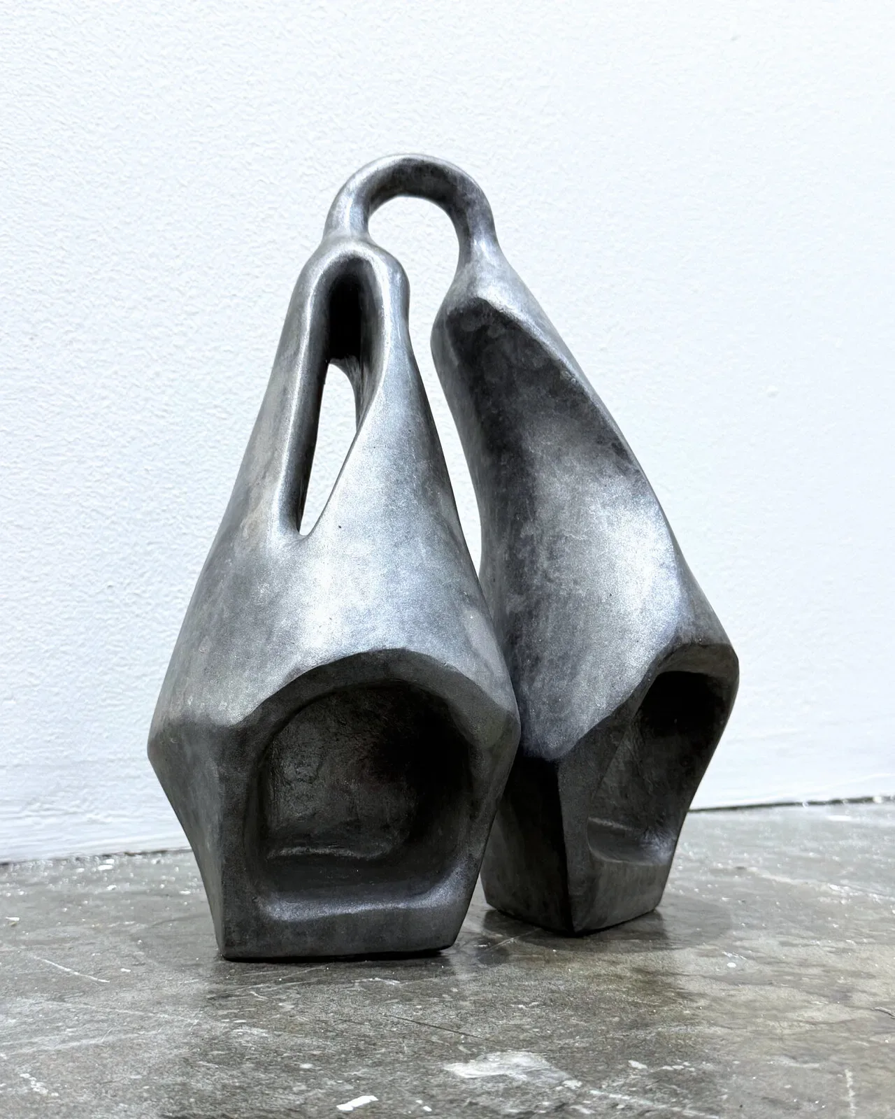 Ogene MIDI: 001 in cast aluminium, three-quarter view — the left form slotted, both mouths open